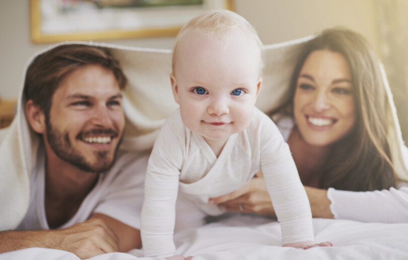 Kinderwunsch: Mutter, Vater und Baby im Bett beim Kuscheln