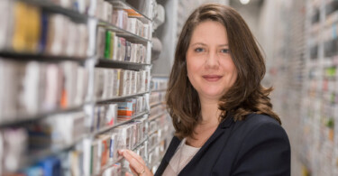 Medpex Apothekerin vor dem Regal mit Medikamenten