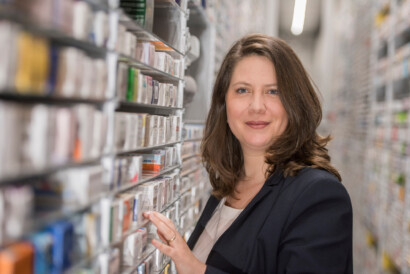 Medpex Apothekerin vor dem Regal mit Medikamenten