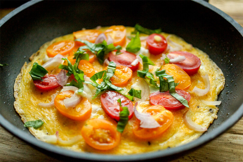 Gesundes Omelette mit Tomaten, Zwiebeln und Basilikum