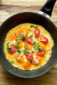 Gesundes Omelette mit Tomaten, Zwiebeln und Basilikum