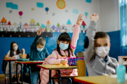Mundschutz für Kinder - Kind meldet sich in der Klasse